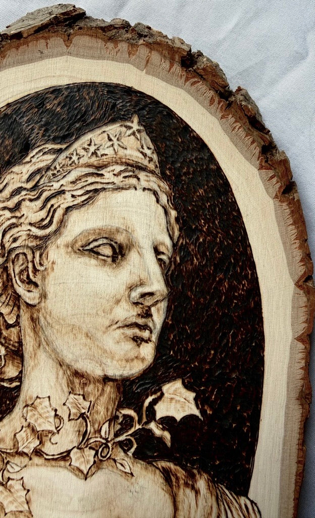 Wood burned wooden portrait of a woman with a crown on a white background
