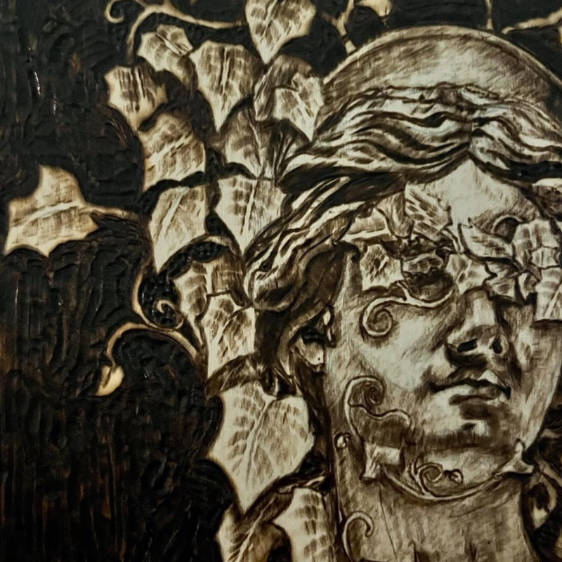 Decorative carving of a face with intricate details and a bird-like creature.