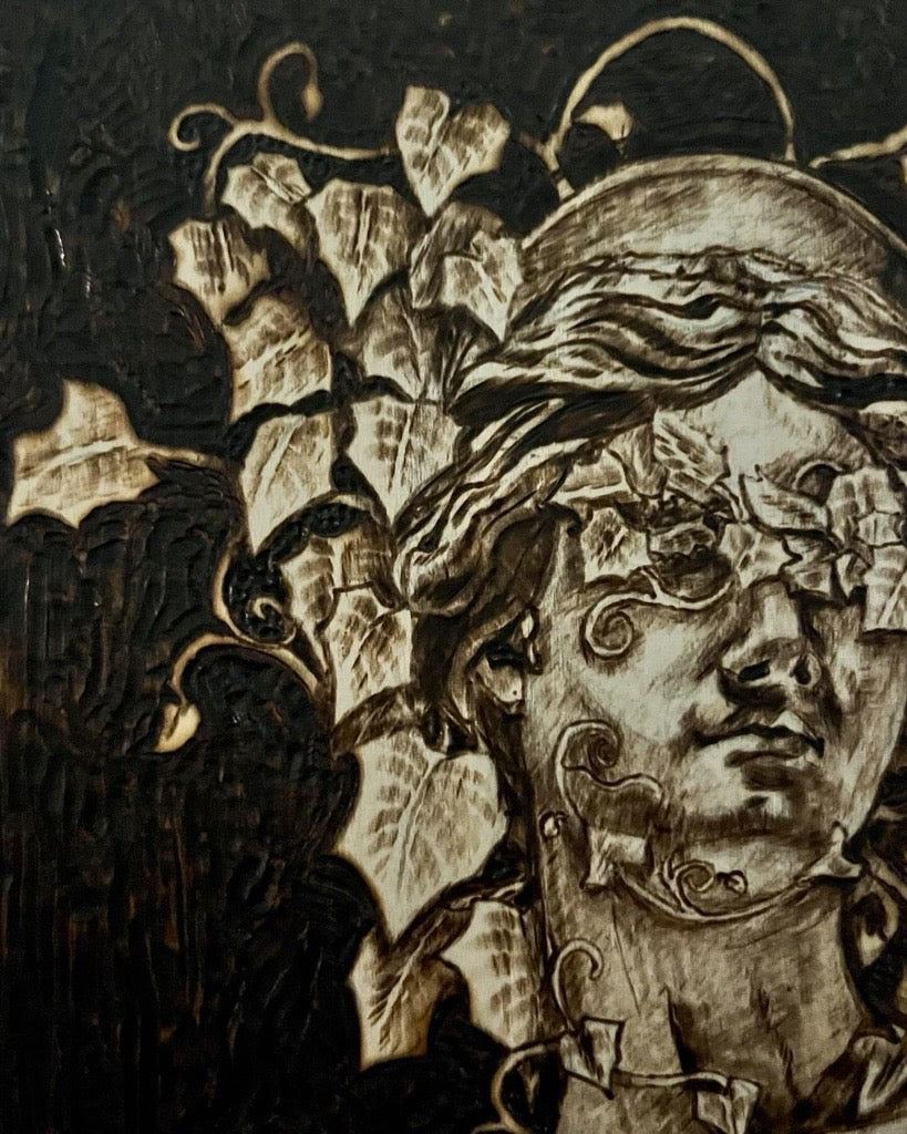 Decorative artwork with a stylized face and leaves on a dark background