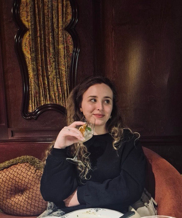 Woman sitting at a table in a restaurant with a plate of food and a glass of water.