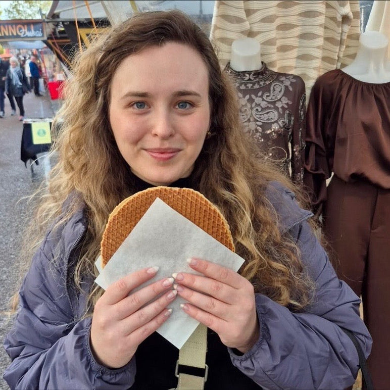 Woman holding a stroopwaffel at an outdoor market in Amsterdam